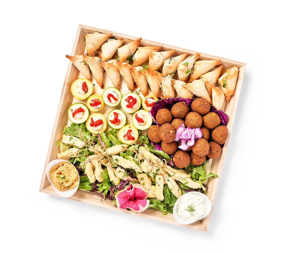 A wooden tray with a variety of snacks, dips, and Mediterranean Party Platter.