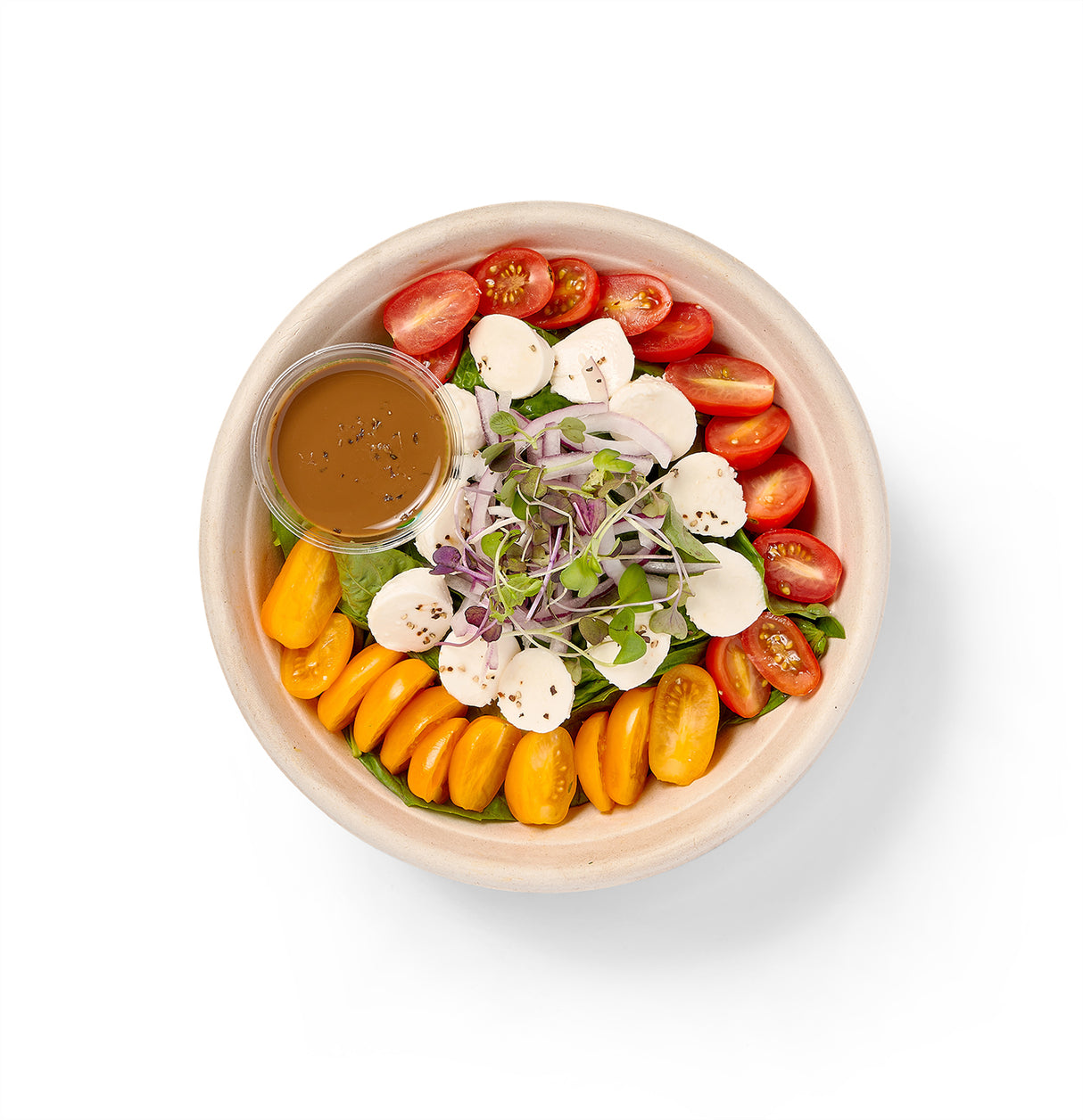 A Caprese Individual Entree Salad with grape tomatoes and creamy burrata on a white background.