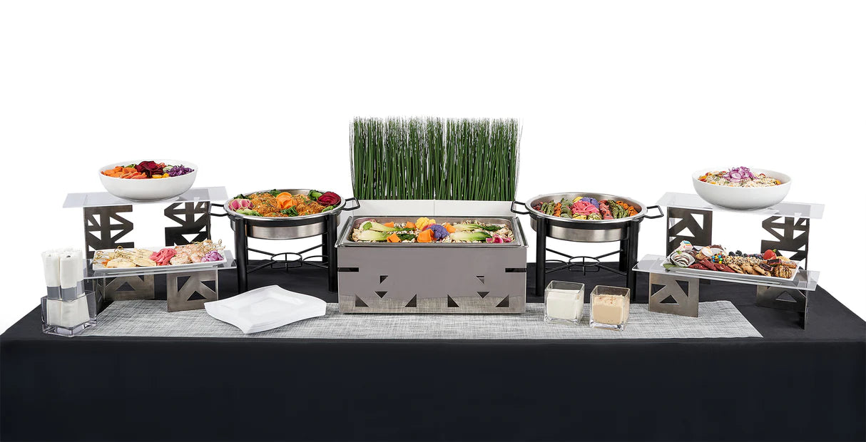The Double Entree Package (TEST - DO NOT USE) features chafing dishes, salads, appetizers, sauces, napkins, and a decorative centerpiece on a black tablecloth—ideal for group meals with diverse dietary needs.
