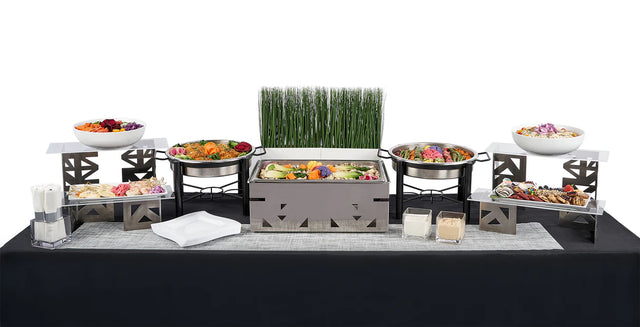 The Double Entree Package (TEST - DO NOT USE) features chafing dishes, salads, appetizers, sauces, napkins, and a decorative centerpiece on a black tablecloth—ideal for group meals with diverse dietary needs.