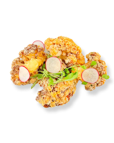 Buffalo Cauliflower Bites are presented with sliced radishes and sprouts on a white background, featuring a hint of buffalo sauce.
