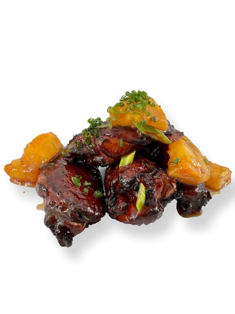 Sweet Chili Wings topped with sliced green onions and herbs, served with caramelized pineapple chunks.