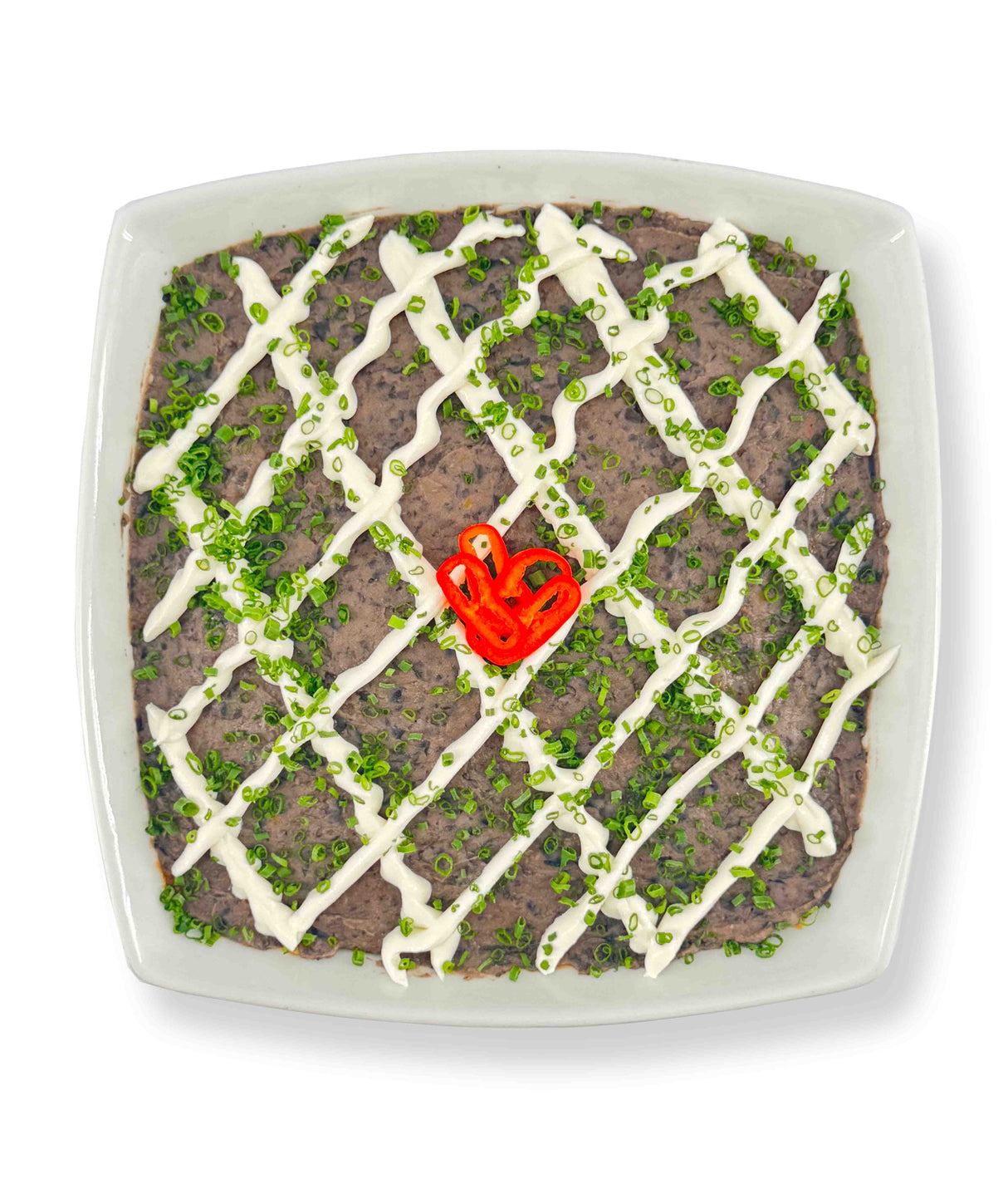 A square dish of 6 Layer Dip topped with Whitestone Cheddar, a mayonnaise drizzle, green onions, and a red chili pepper slice in the center. Serve with guacamole and corn tortillas for a complete flavor experience.