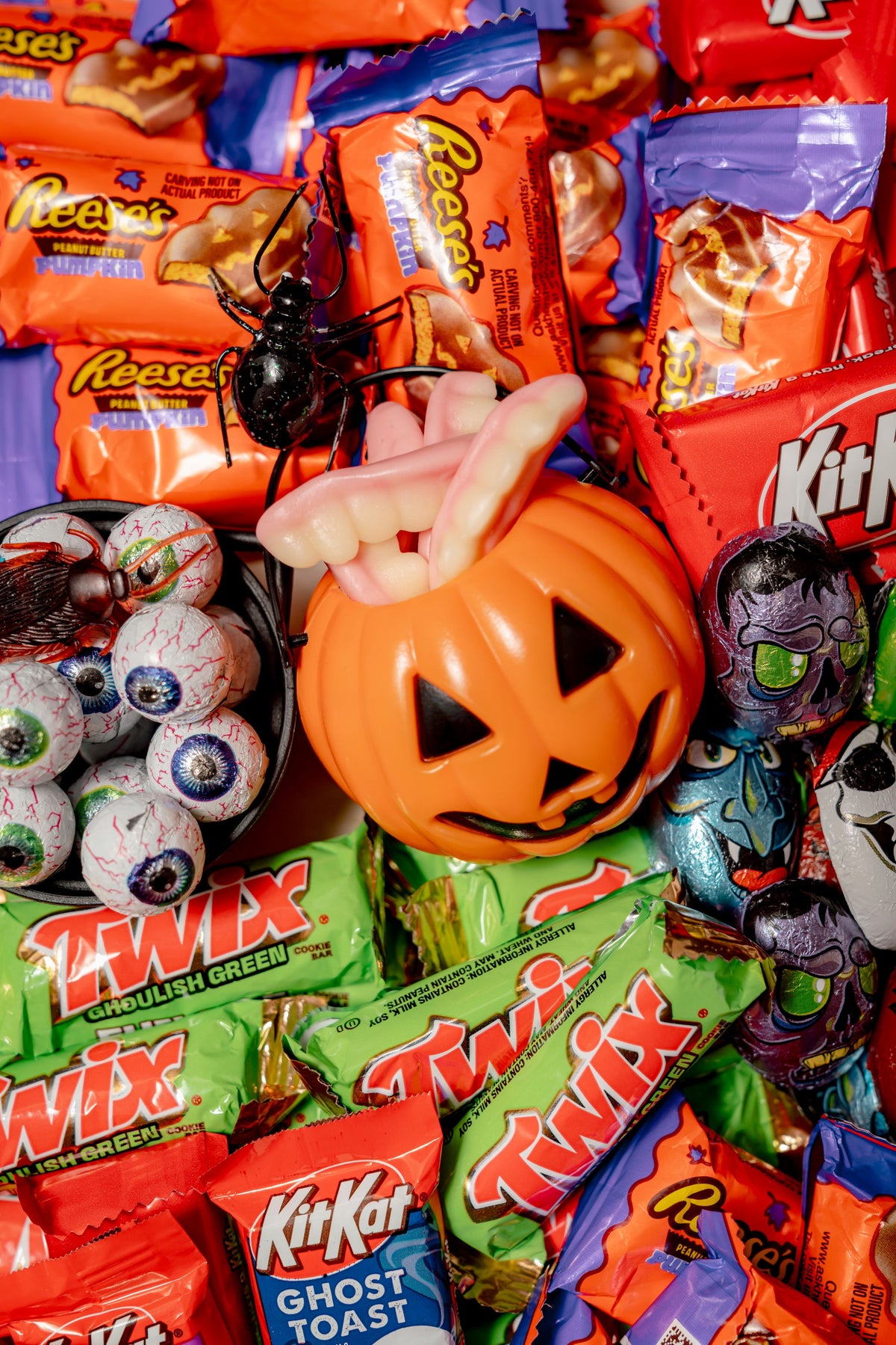 A Dr. Frankenstein’s Candy Lab Party Platter featuring a plastic jack-o’-lantern bowl filled with gummy worms and candy corn, surrounded by gummy teeth, chocolate eyeballs, and a black spider toy.