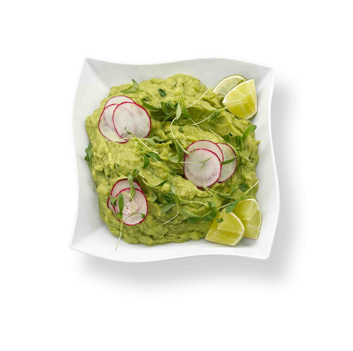 Vegetable Crudite with Guacamole in a square white dish, garnished with radish slices, fresh cilantro, microgreens, and lime wedges on a pristine white background.