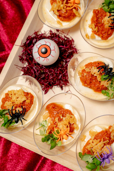 Bloody Burrata: individual servings of burrata topped with Calabrian sundried pesto and micro basil, served on a tray with a decorative eyeball and small plastic spiders.