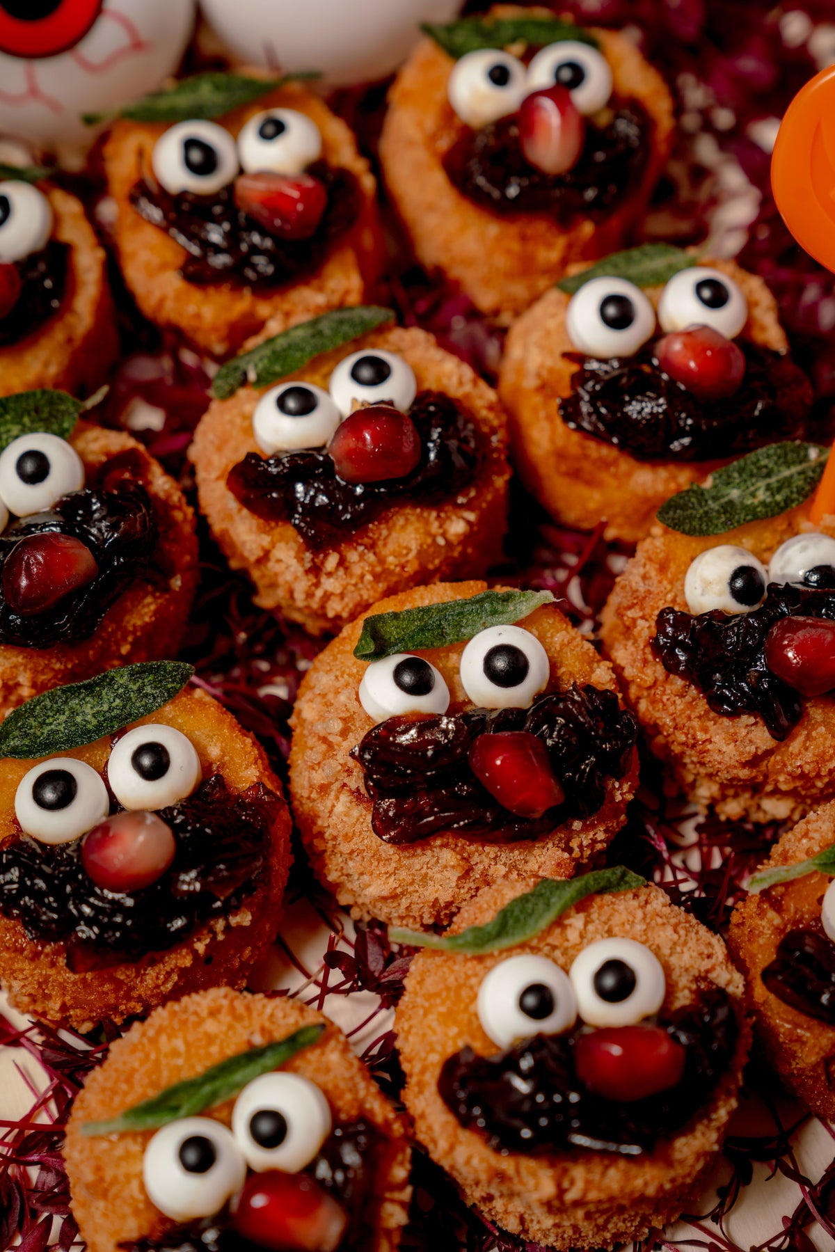Eyeball Arancini, consisting of deep-fried vegetarian butternut squash risotto balls decorated to look like spooky eyeballs with dark jam and pomegranate seeds.