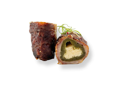 Two slices of Jalapeno Poppers, one cut open to show cream cheese and Pepper Jack filling, garnished with green onion on a white background.