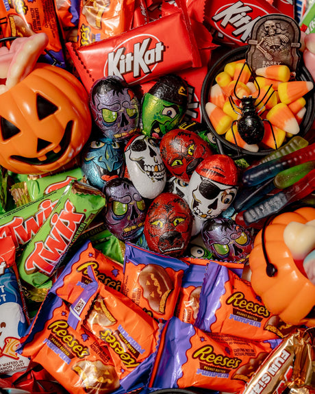 Dr. Frankenstein’s Candy Lab Party Platter includes chocolate bars, pumpkin-shaped peanut butter cups, skull-themed chocolates, gummy worms, and a cauldron filled with candy corn and a toy spider.