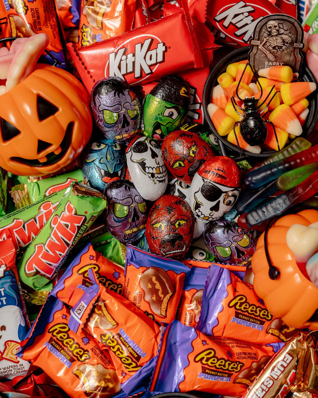 Dr. Frankenstein’s Candy Lab Party Platter includes chocolate bars, pumpkin-shaped peanut butter cups, skull-themed chocolates, gummy worms, and a cauldron filled with candy corn and a toy spider.