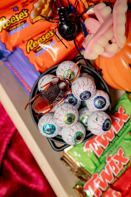 Dr. Frankenstein’s Candy Lab Party Platter featuring a small black cauldron filled with foil-wrapped eyeball candies, gummy worms, and a plastic cockroach, surrounded by candy bars and vampire teeth.