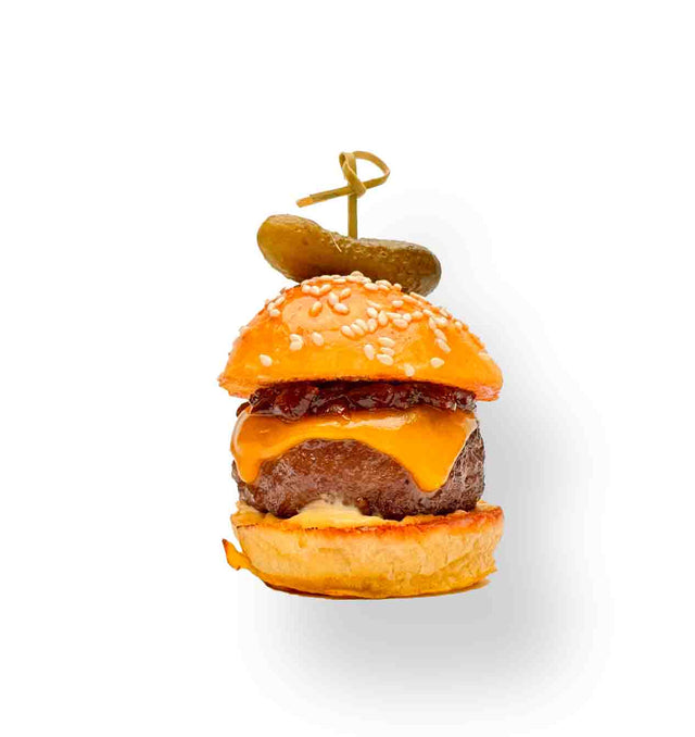 The PFD Premium Aged Beef Slider includes a juicy beef patty, melted cheddar, and savory sauce on a Mini Martin Potato Bun, topped with a small pickle secured by a toothpick.