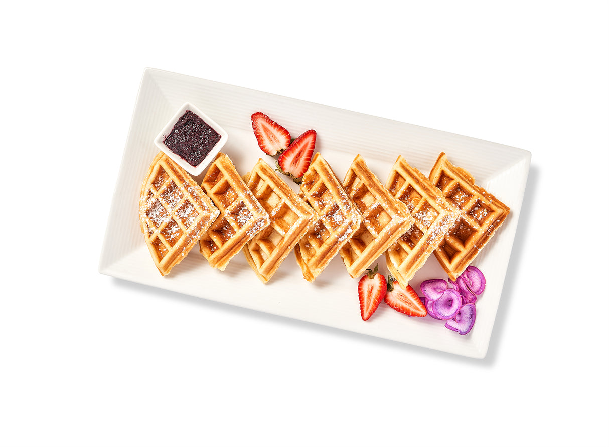 Two pieces of Homemade Waffles with strawberries, raspberries, and sweet butter on a white plate.