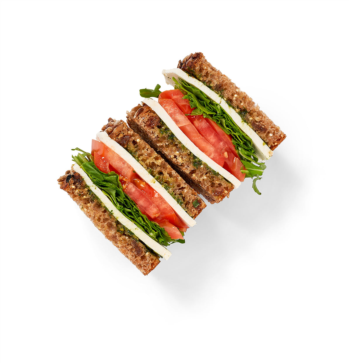 The Stracciatella and Tomato Sandwich features whole grain bread topped with cheese, herb roasted tomatoes, and leafy greens, all photographed from above on a white background.