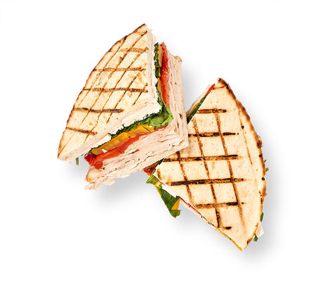 A Cuban Panini sandwich is cut in half on a white background.