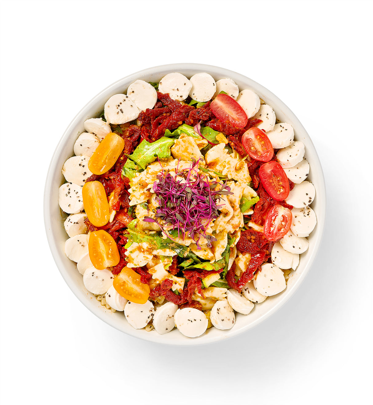 A bowl filled with Bowtie Pasta Salad and a variety of zucchini, squash, and a few other vegetables.