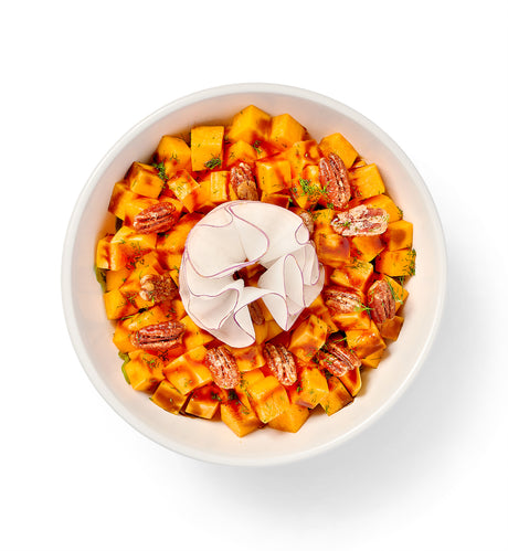 A bowl of Balsamic Glazed Sweet Potatoes salad with pecans in it.