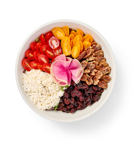 A bowl filled with fruit, sundried cranberries, nuts and Paradise Salad.