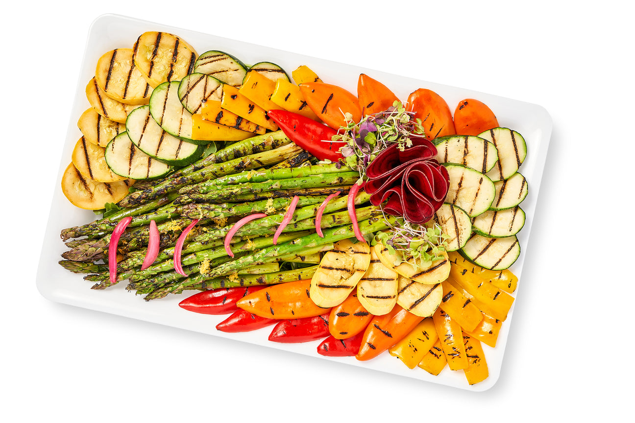 A plate of Grilled Seasonal Vegetables with a White Balsamic Drizzle on a white background.