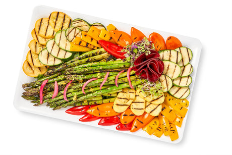 A plate of Grilled Seasonal Vegetables with a White Balsamic Drizzle on a white background.